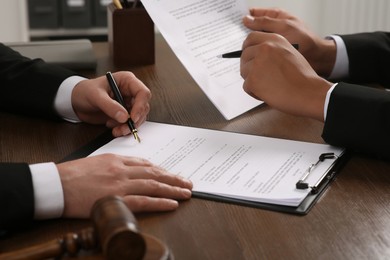 Photo of Law and justice. Lawyers working with documents at wooden table, closeup