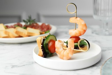 Photo of Tasty canapes with shrimps, cucumber, greens and tomatoes on white marble table