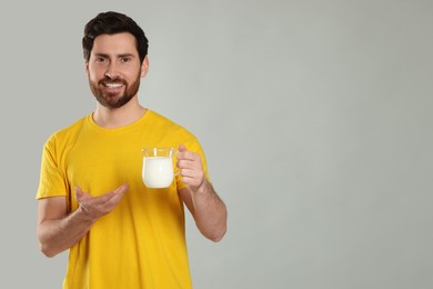 Photo of Handsome man with delicious yogurt on light grey background. Space for text
