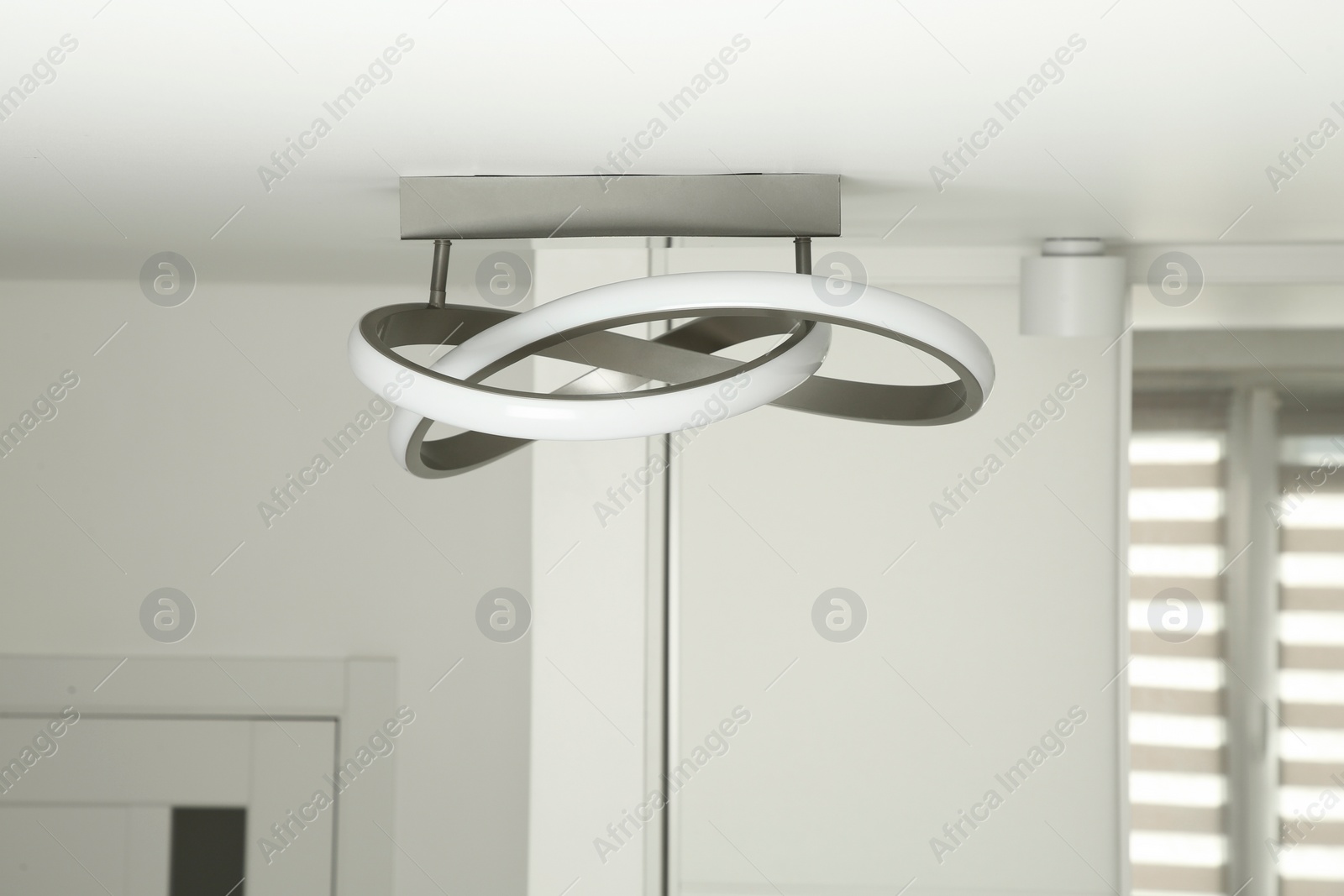 Photo of White ceiling with stylish lamp in room. Space for text