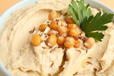 Photo of Bowl of tasty hummus with chickpeas and parsley, closeup