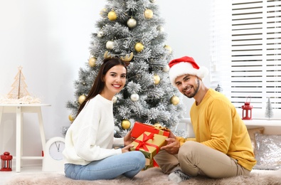 Photo of Happy young couple exchanging Christmas gifts at home