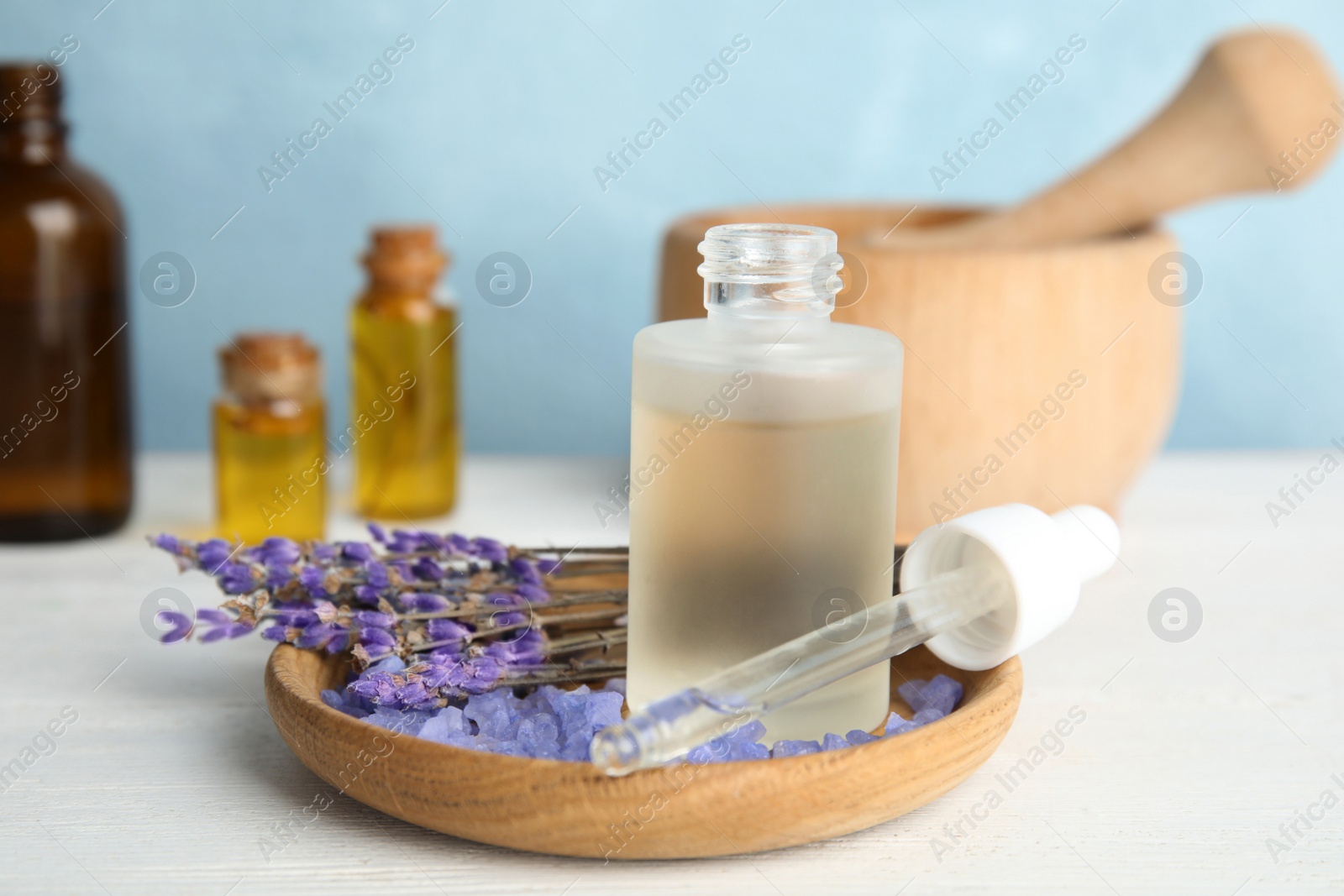 Photo of Bottle with aromatic lavender oil on wooden table