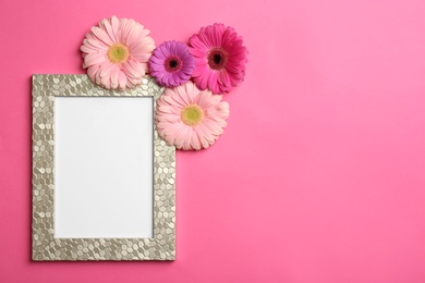 Photo of Flat lay composition with stylish photo frame and beautiful flowers on color background, space for text