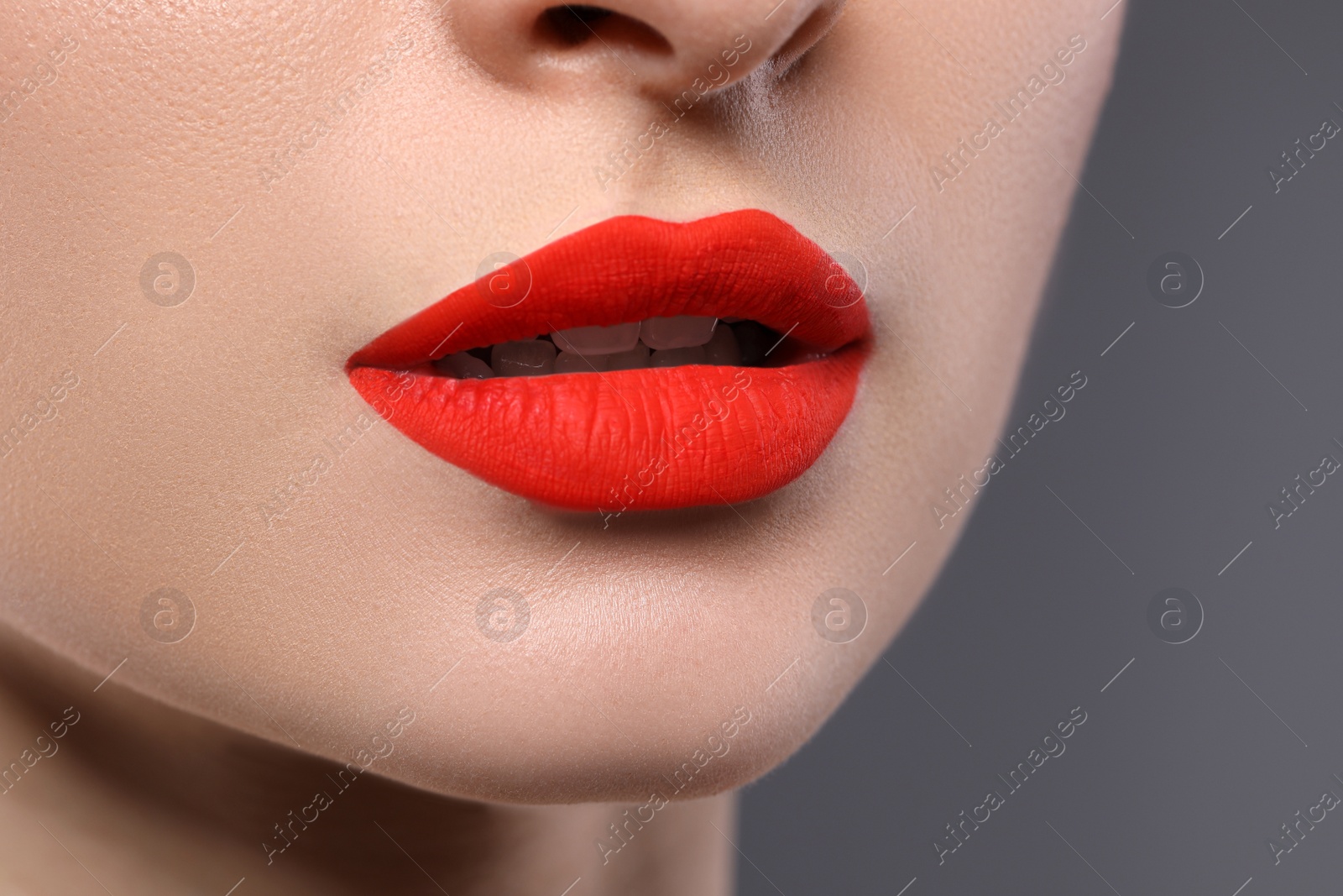 Photo of Young woman with beautiful red lips on grey background, closeup