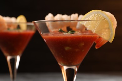 Photo of Tasty shrimp cocktail with sauce in glasses and lemon on table, closeup