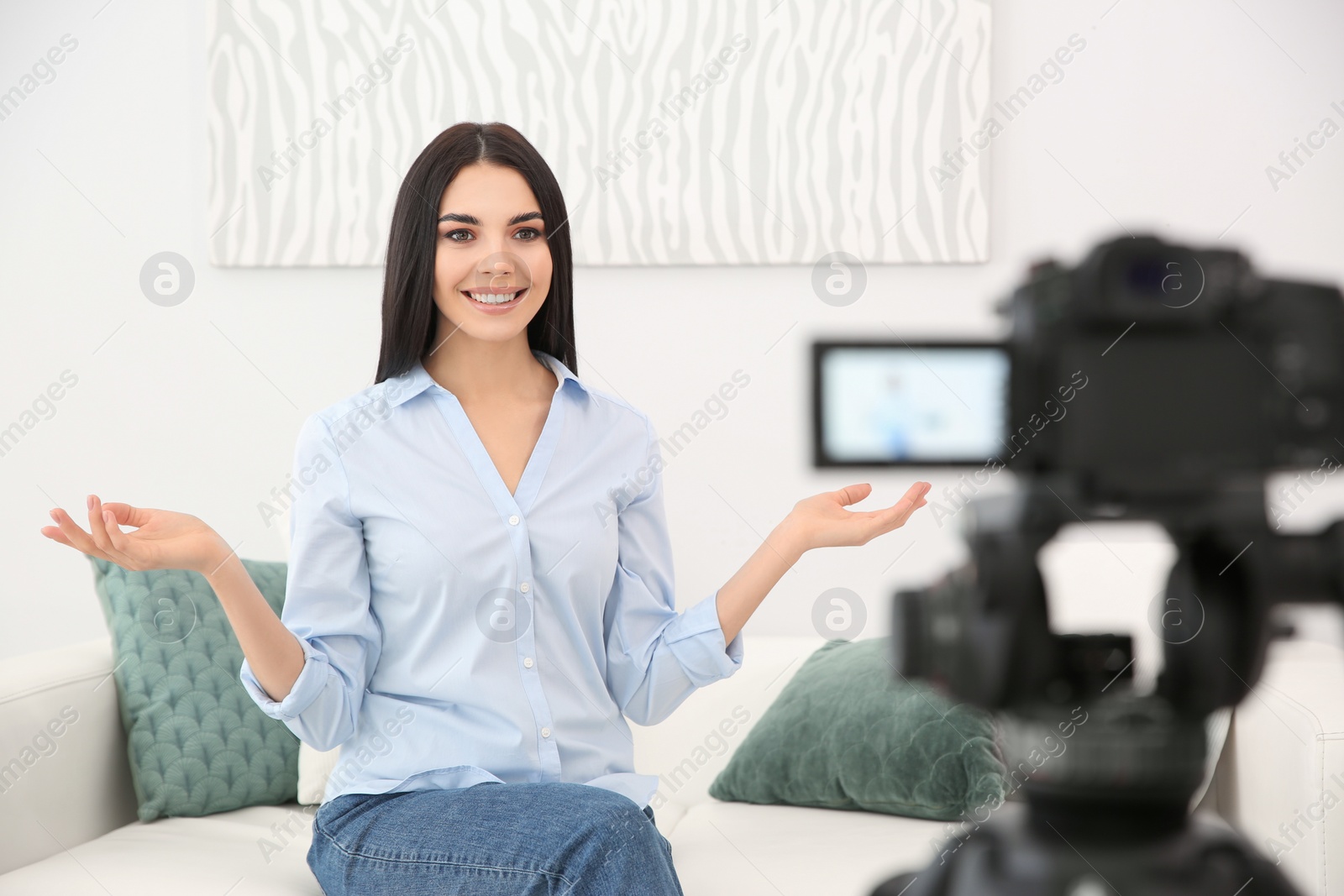 Photo of Young blogger recording video on camera indoors