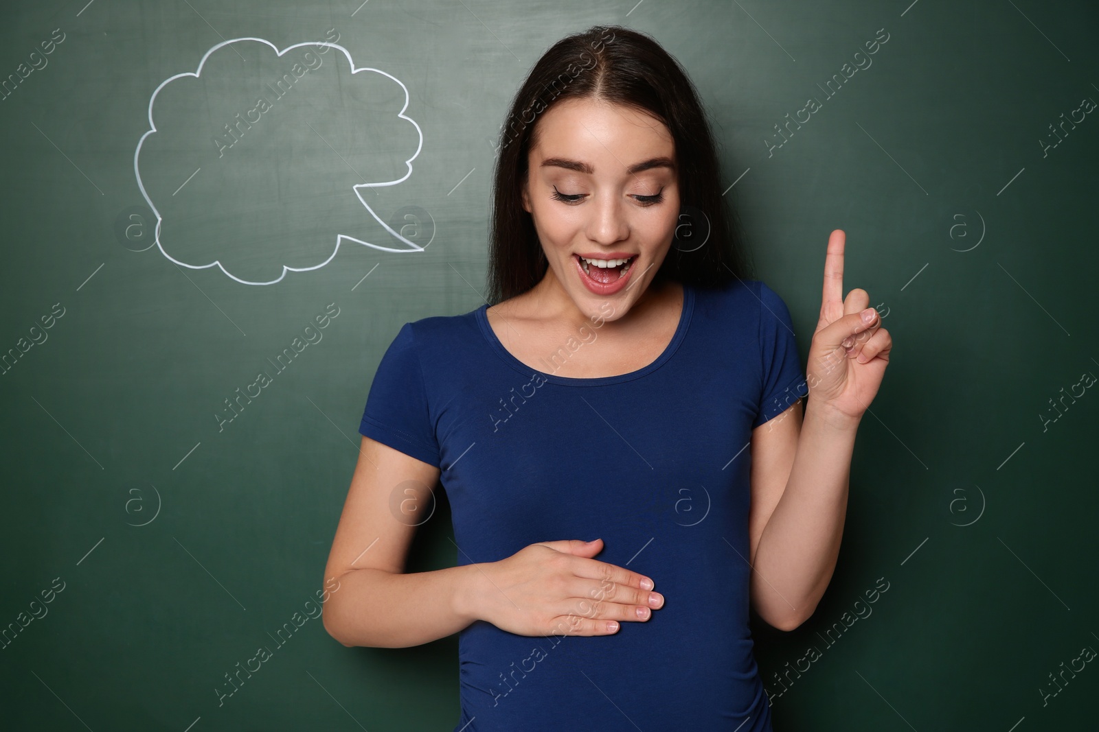 Photo of Pregnant woman thinking about baby name near green chalkboard