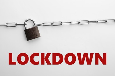 Image of Concept of lockdown due to Coronavirus pandemic. Steel padlock and chain isolated on white, top view