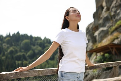 Feeling freedom. Beautiful woman enjoying nature near wooden railing in mountains