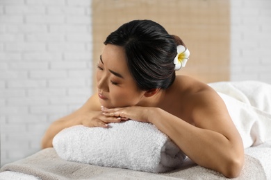 Photo of Beautiful Asian woman lying on massage table in spa salon