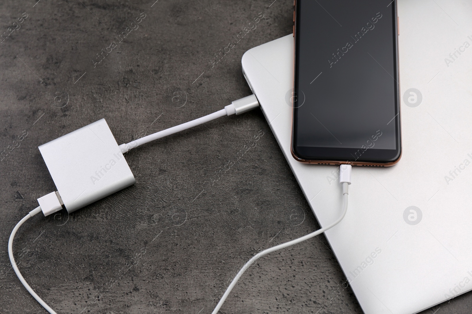 Photo of Modern smartphone and laptop charging from power bank on grey table, above view