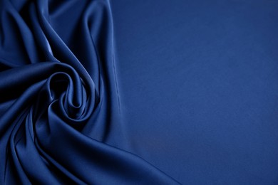Photo of Crumpled dark blue silk fabric as background. Space for text