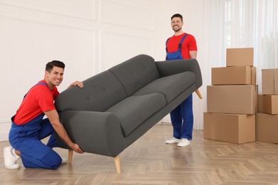 Professional movers carrying sofa in new house