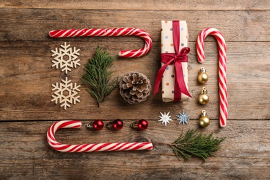 Photo of Flat lay composition with candy canes and Christmas decor on wooden background