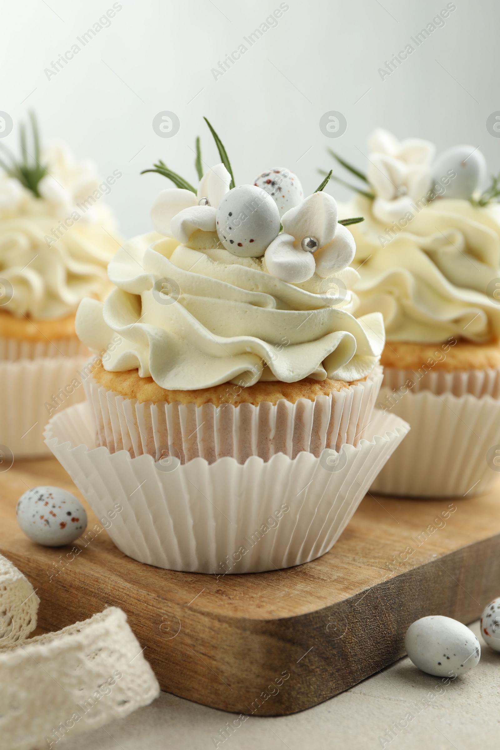 Photo of Tasty Easter cupcakes with vanilla cream on gray table, closeup