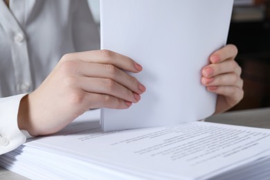 Woman stacking documents at table in office, closeup
