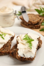 Photo of Bread with cream cheese and arugula on plate, closeup