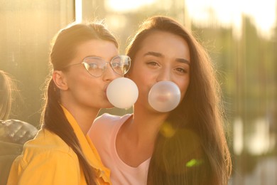 Photo of Beautiful young women blowing bubble gums outdoors on sunny day