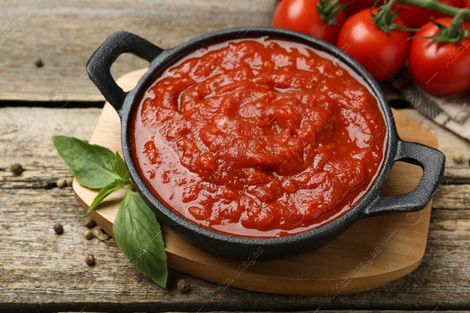 Photo of Homemade tomato sauce in bowl and basil on wooden table, closeup