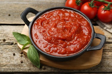 Photo of Homemade tomato sauce in bowl and basil on wooden table, closeup