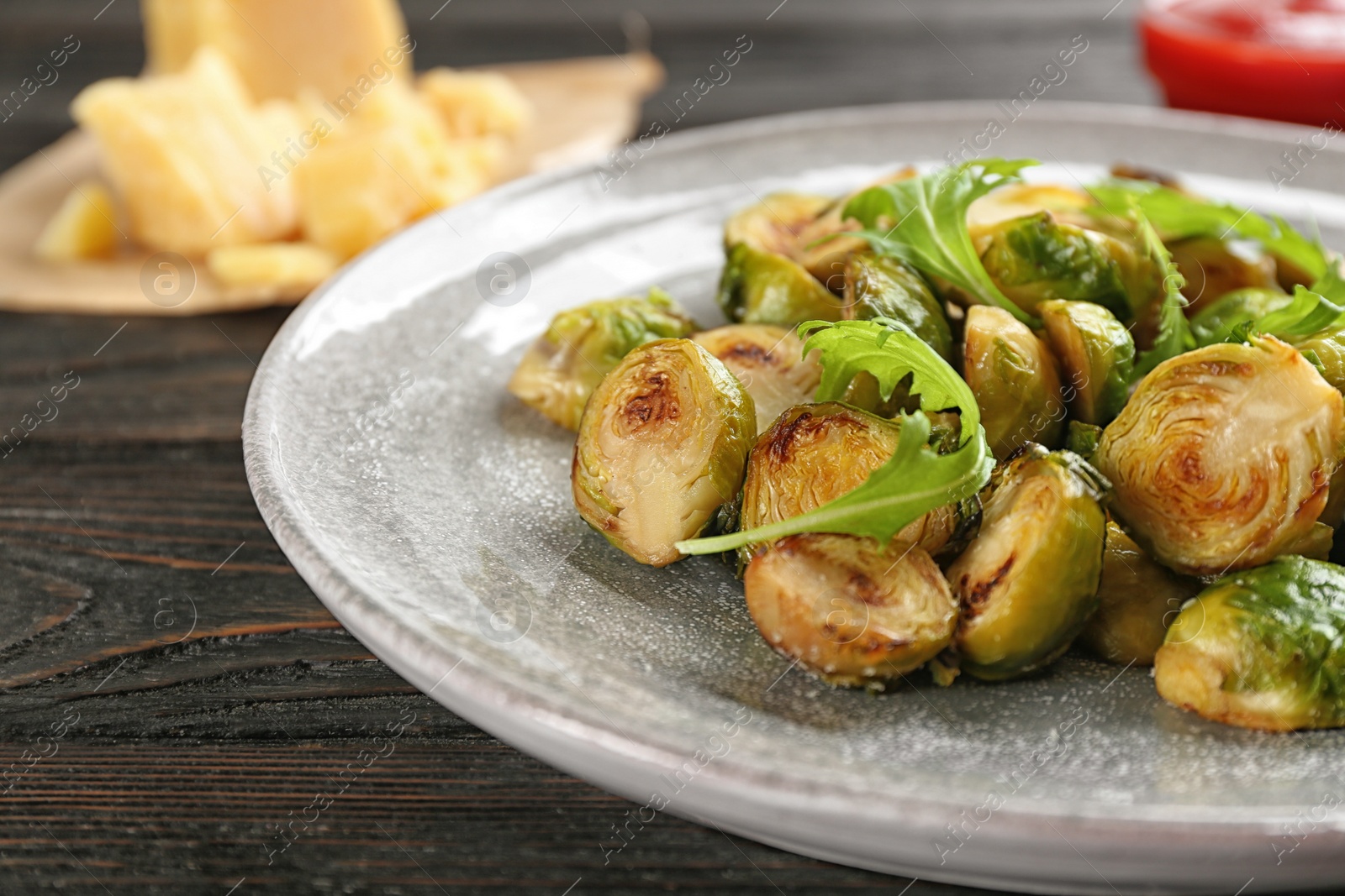 Photo of Delicious roasted brussels sprouts with arugula on table, closeup