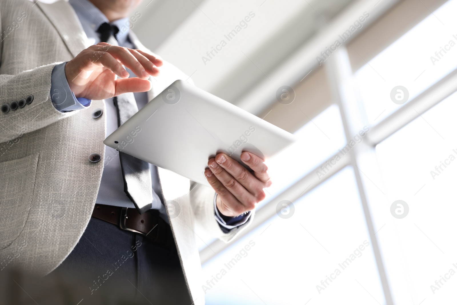 Photo of Closeup view of businessman working with modern tablet in office, low angle view