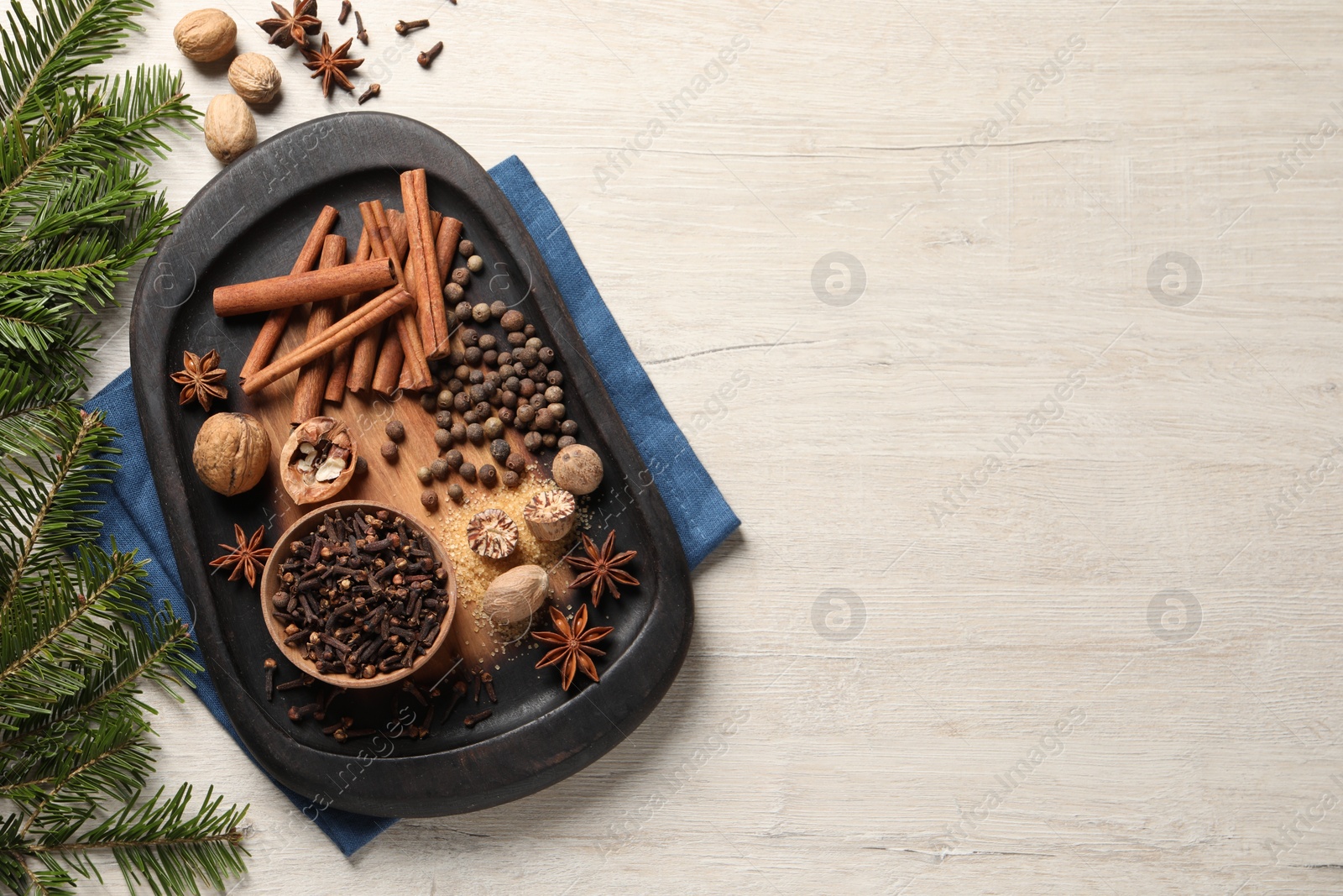 Photo of Different spices, nuts and fir branches on wooden table, flat lay. Space for text