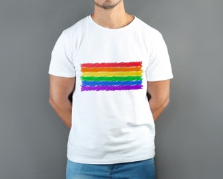 Image of Young man wearing white t-shirt with image of LGBT pride flag on grey background
