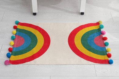 Photo of Stylish rug with rainbow on floor indoors