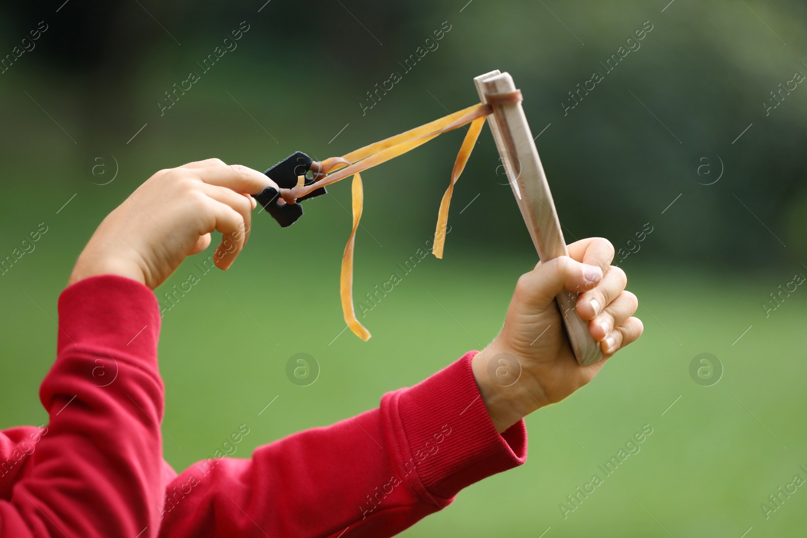 Photo of Little boy playing with slingshot outdoors, closeup