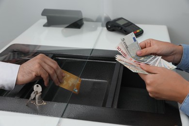 Photo of Woman putting money on card in bank, closeup. Currency exchange