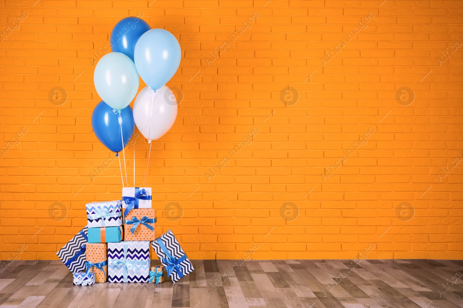 Image of Many gift boxes and balloons near orange brick wall. Space for text