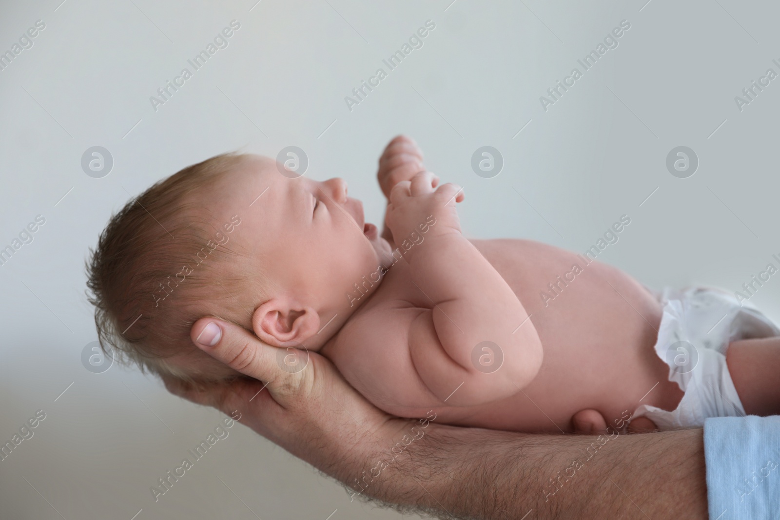 Photo of Father holding his newborn baby at home, closeup