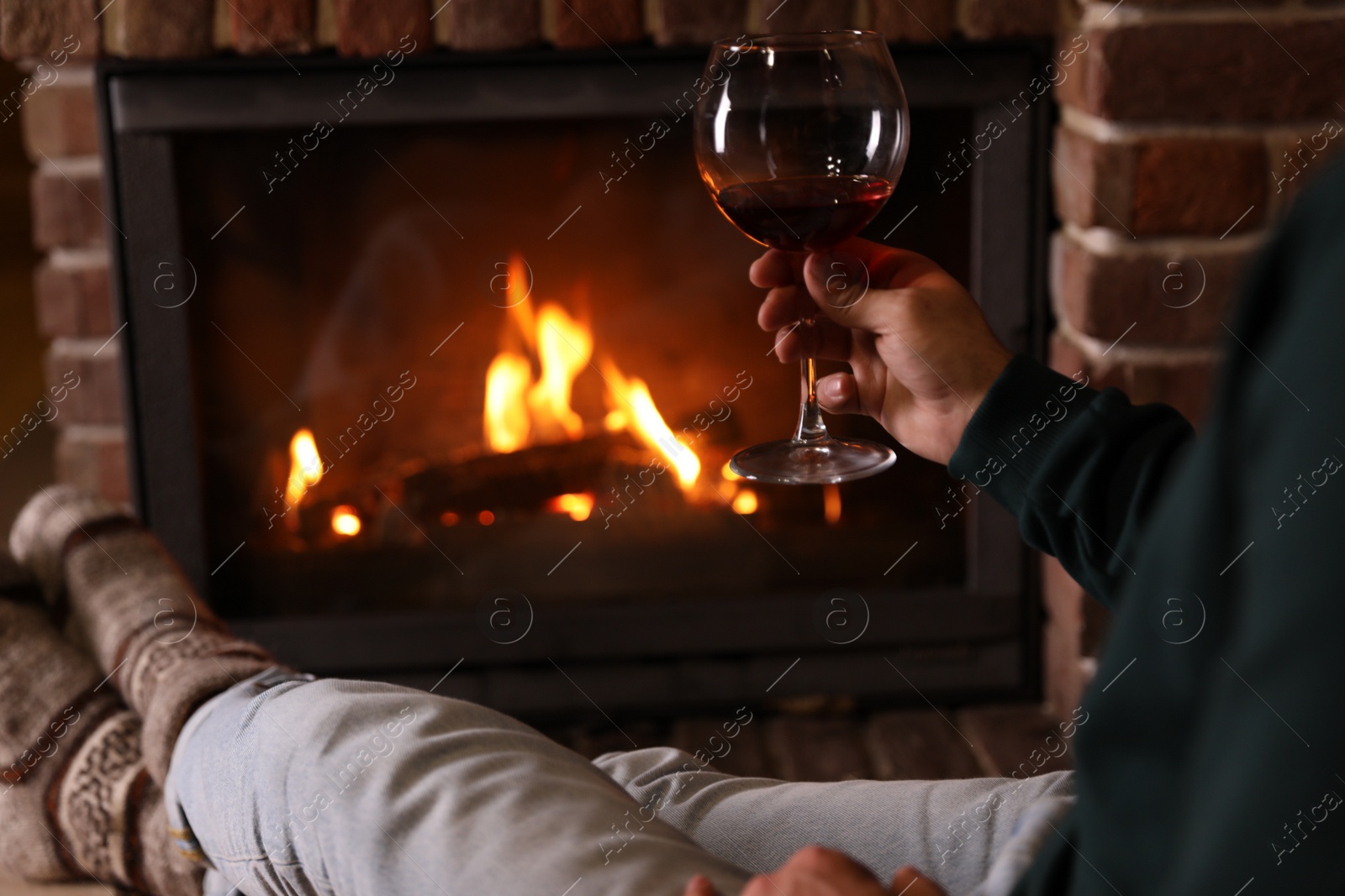 Photo of Man with glass of wine near fireplace at home, closeup