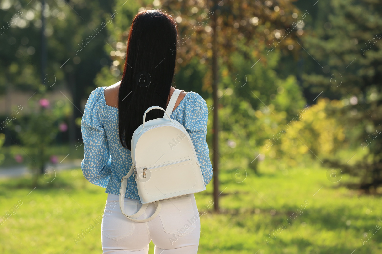 Photo of Young woman with stylish white backpack in park, back view. Space for text