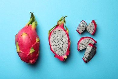 Photo of Delicious cut and whole white pitahaya fruits on light blue background, flat lay