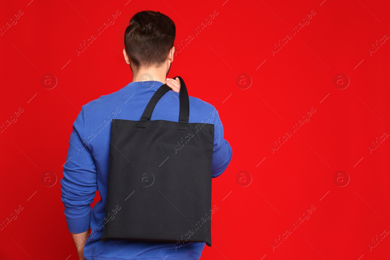 Photo of Young man with eco bag on red background. Space for text