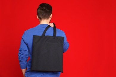 Photo of Young man with eco bag on red background. Space for text