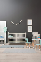 Photo of Cute baby room interior with modern crib near dark wall
