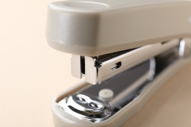 Photo of One new stapler on beige background, closeup