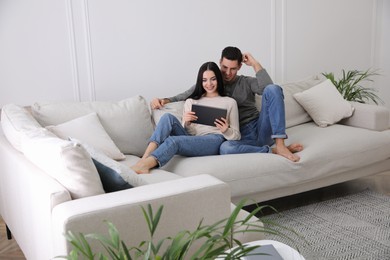 Couple with tablet resting on sofa in living room