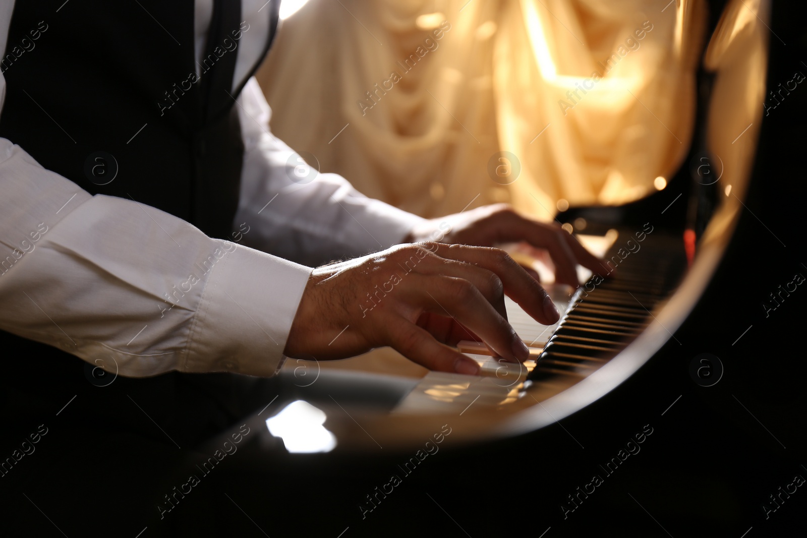 Photo of Man playing piano indoors, closeup. Talented musician