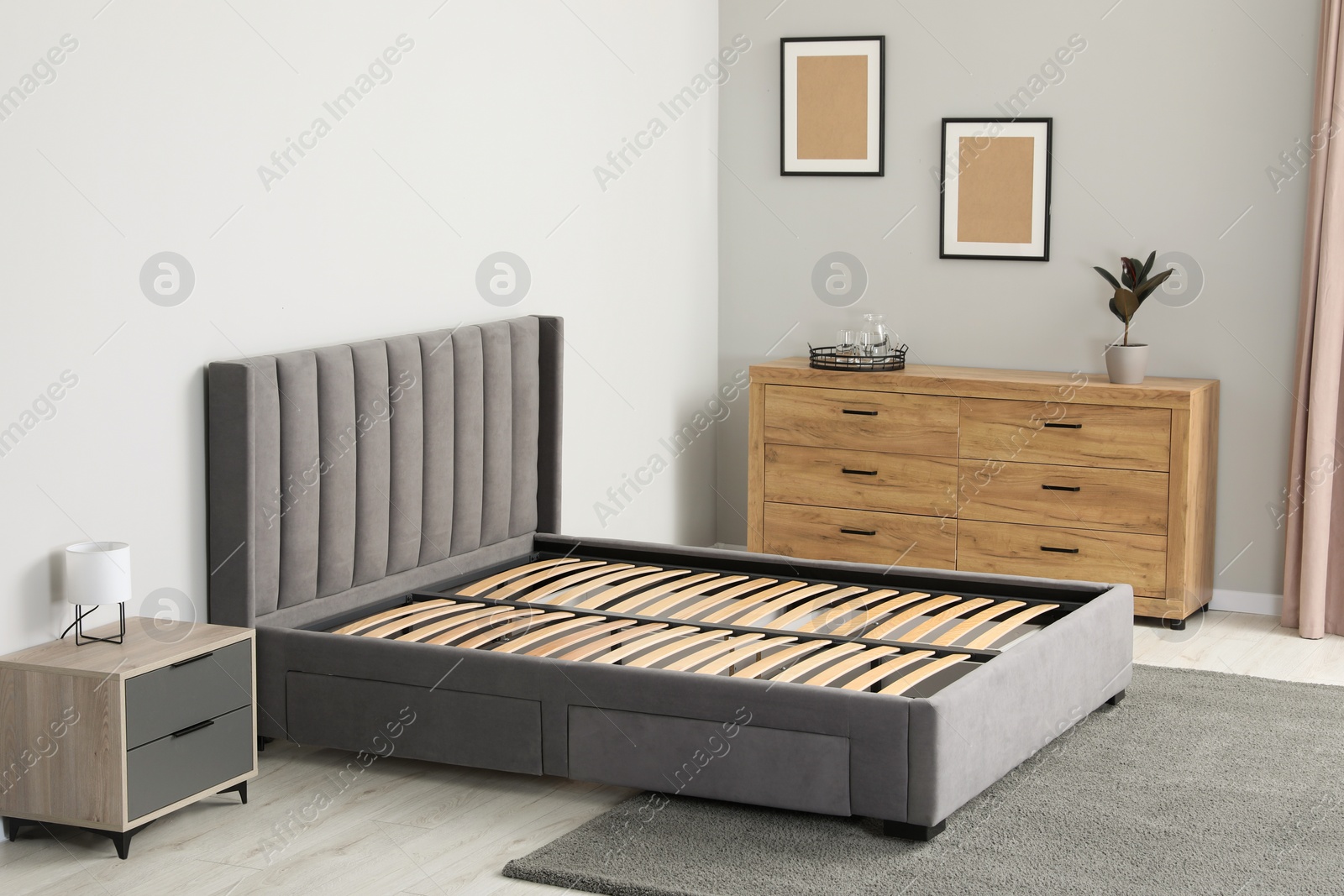 Photo of Comfortable bed with storage space for bedding under slatted base in stylish room