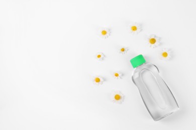 Photo of Transparent bottle with baby oil and daisies on white background, flat lay. Space for text
