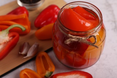 Jar with tasty pickled peppers and fresh vegetables on table, closeup. Space for text