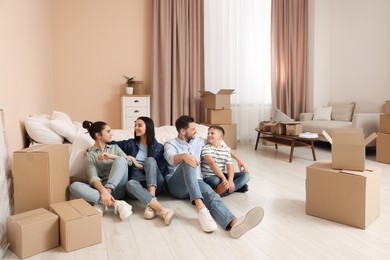 Photo of Happy family resting on floor near boxes in new apartment. Moving day