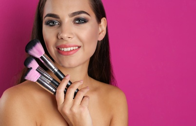 Photo of Portrait of beautiful woman with makeup brushes on color background. Space for text