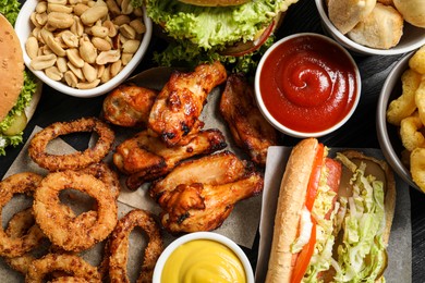 Chicken wings, onion rings and other fast food as background, top view