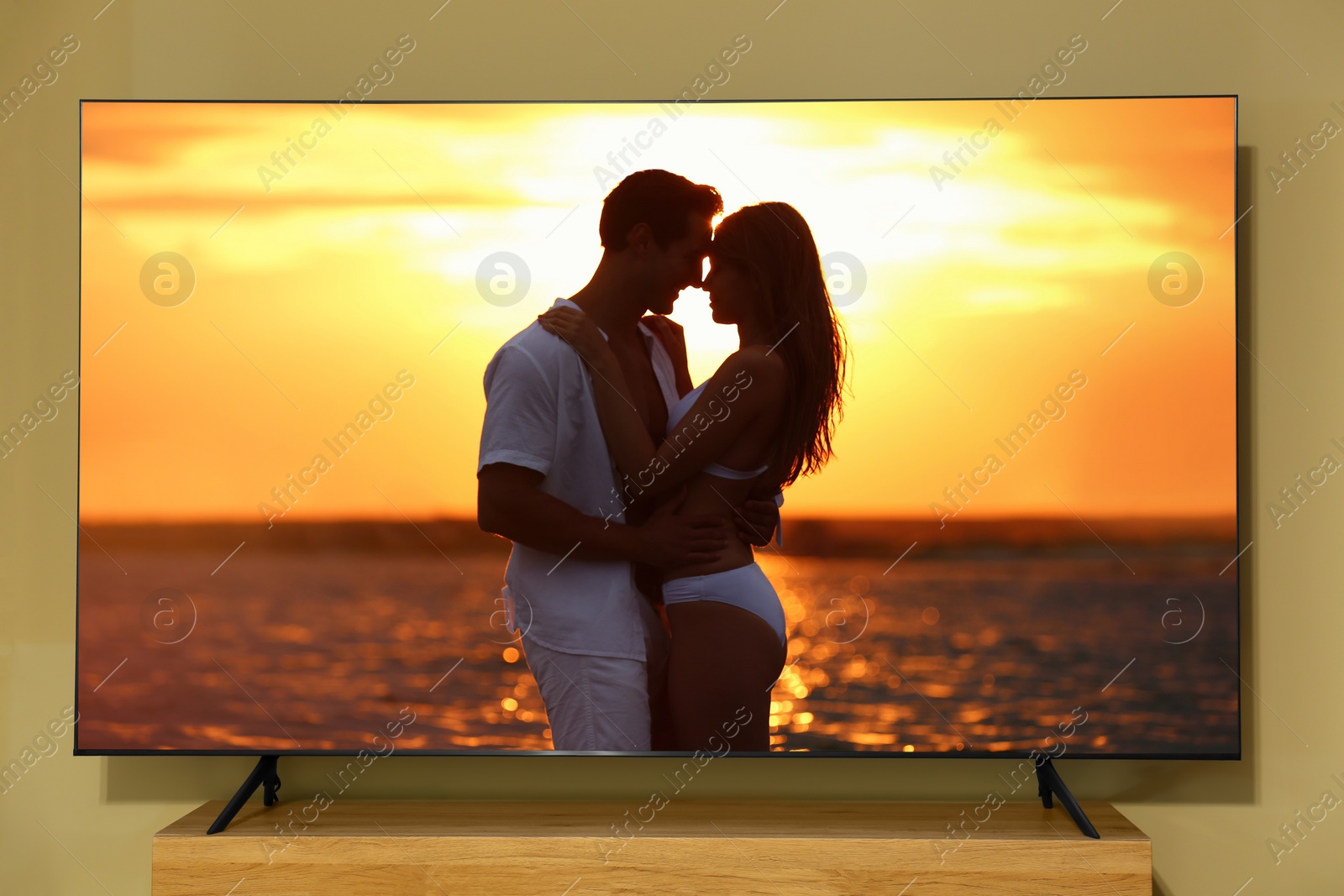 Image of Tv near beige wall. Romantic movie on screen